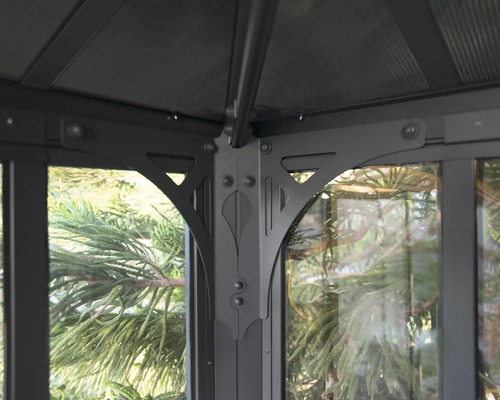 Detailní pohled na altán se skleněnými prvky a kovovým rámem.