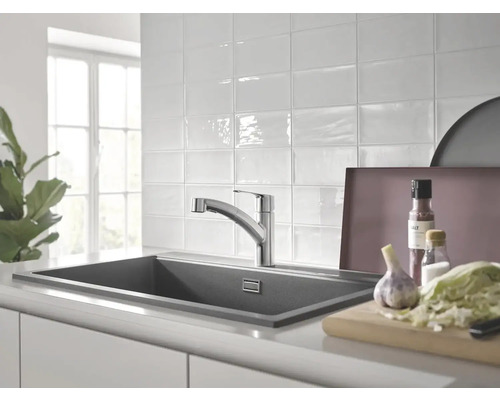 Kuchyňská scéna s dřezem, vodovodní baterií a potravinami na pracovní desce.