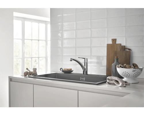 Kuchyňská scéna s dřezem, vodovodní baterií a příslušenstvím před bílým obkladem