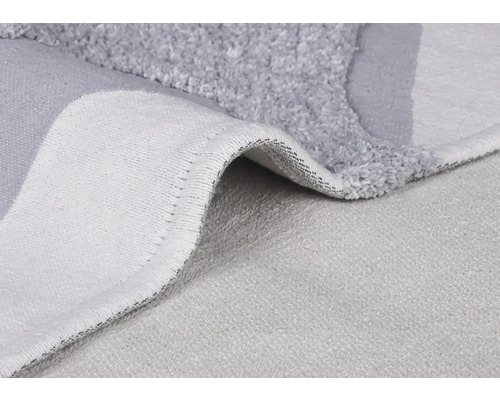 Detail šedé koupelnové předložky s vlasem a tkanou zadní stranou.