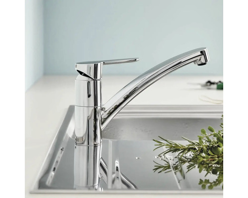 Chromovaná kuchyňská baterie nad dřezem.