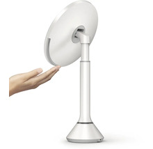 Bílé kosmetické zrcadlo se stojanem a rukou na obrázku.