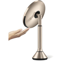 Kosmetické zrcadlo na podstavci s rukou, která se ho dotýká