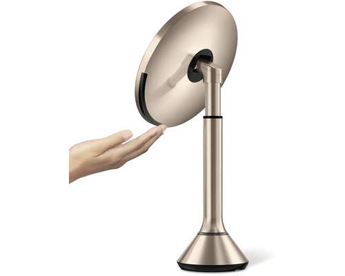 Kosmetické zrcadlo na podstavci s rukou, která se ho dotýká