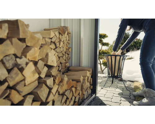 Žena plní koš na oheň dřevem z regálu na dřevo