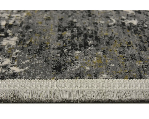 Detailní pohled na koberec s abstraktním vzorem a třásněmi