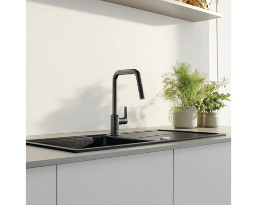 Černý kuchyňský dřez s vodovodní baterií v moderní kuchyni.