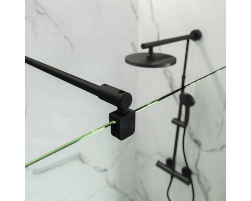 Detailní záběr sprchového koutu s černým držákem a sprchovou hlavicí před mramorovou stěnou