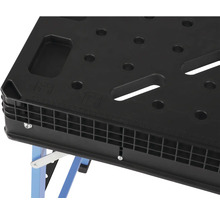 Detailní pohled na pracovní stůl s děrovanou deskou a modrýma nohama.