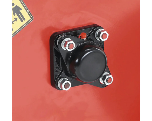 Detailní záběr černého krytu připevněného šrouby k červenému povrchu