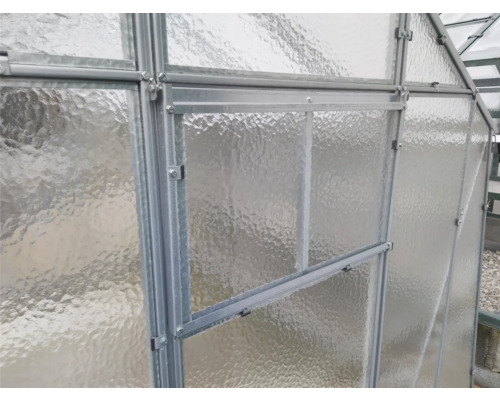 Detail skleníkové stěny s texturovaným sklem a kovovým rámem