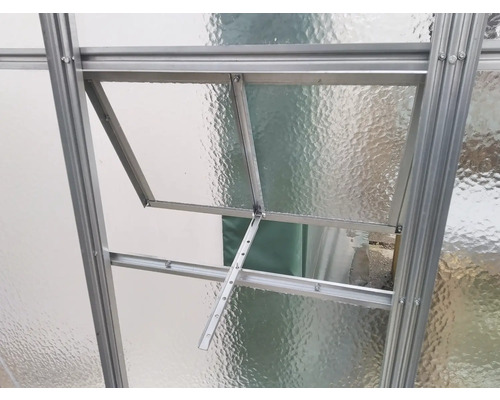 Detailní pohled na okno skleníku s hliníkovým rámem a průsvitným sklem