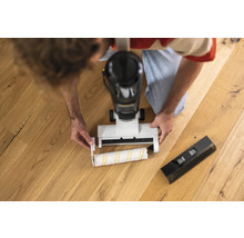 Muž vyměňuje čisticí válec elektrického mopu na dřevěné podlaze