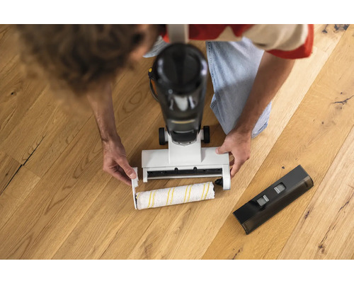 Muž vyměňuje čisticí válec elektrického mopu na dřevěné podlaze