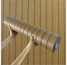 Role nábytkové fólie s dřevěným designem držená v rukou