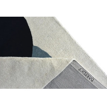 Detailní záběr na koberec s abstraktními geometrickými tvary, zobrazující povrch vlasu a zadní stranu s Bakero Logo.