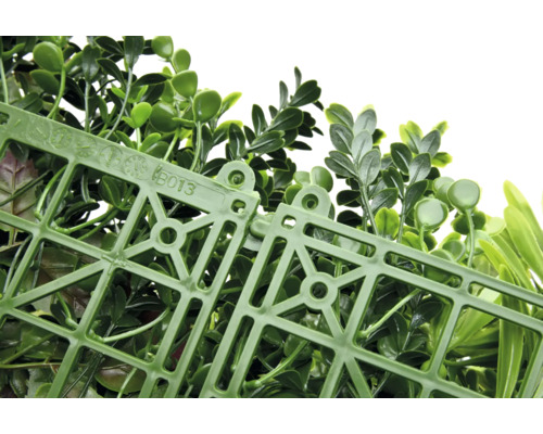 Umělá rostlinná stěna se zelenými listy a plastovou mřížkou