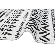 Koberec s geometrickým vzorem a cikcak designem, tkaná textura, černá a bílá.