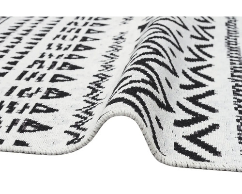 Koberec s geometrickým vzorem a cikcak designem, tkaná textura, černá a bílá.