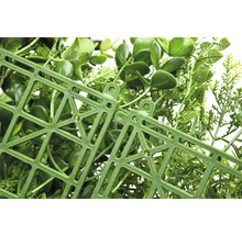 Detailní záběr umělého živého plotu s plastovou mřížkou na zadní straně.