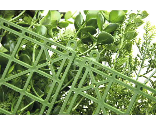 Detailní záběr umělého živého plotu s plastovou mřížkou na zadní straně.