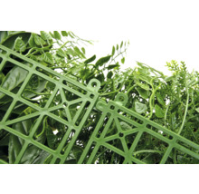 Detailní pohled na umělý živý plot se zelenými listy a plastovou mřížkou