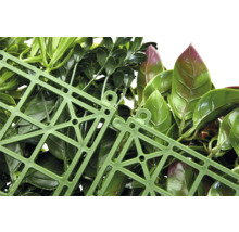 Detailní záběr umělého živého plotu se zelenými listy a zelenou plastovou mřížkou