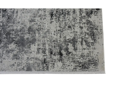 Detailní záběr na koberec v šedých tónech s abstraktním vintage vzorem a sepraným vzhledem.