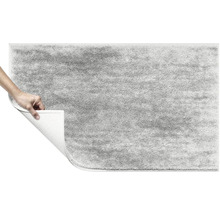 Šedý koberec s vysokým vlasem se zvednutým rohem ukazujícím zadní stranu