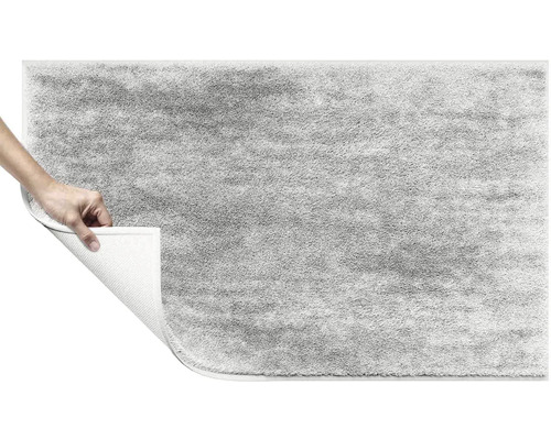 Šedý koberec s vysokým vlasem se zvednutým rohem ukazujícím zadní stranu