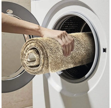 Osoba vkládá koberec do pračky.