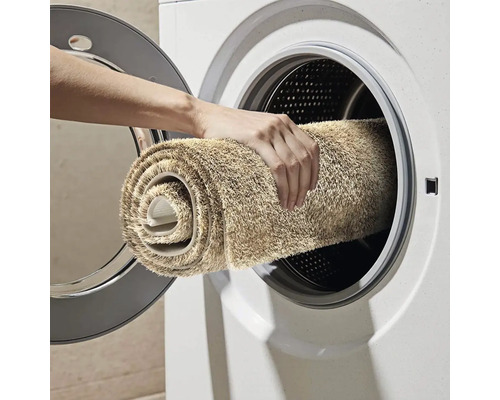 Osoba vkládá koberec do pračky.