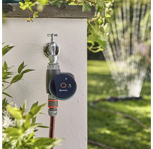 Řídicí jednotka zavlažování Gardena Smart Water Control na vodovodním kohoutku se zahradní hadicí a zavlažovačem trávníku