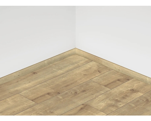 Položená laminátová podlaha s odpovídající soklovou lištou u stěny místnosti