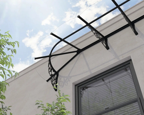 Vchodová stříška s průhlednou střechou a ozdobnými černými kovovými konzolami nad oknem.