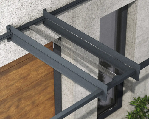 Detail vchodové stříšky s antracitovým hliníkovým rámem a průhlednou skleněnou výplní na fasádě domu.