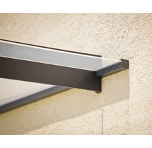 Detail úchytu moderní skleněné stříšky s tmavým kovovým rámem na strukturované stěně.