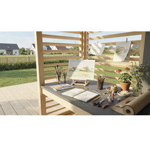 Kreativní pracovní prostor venku s malířským stojanem, barvami, štětci, papírem a květinami