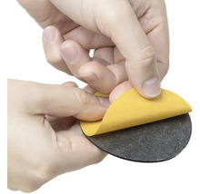 Osoba odstraňuje ochrannou fólii z kulatého nábytkového kluzáku