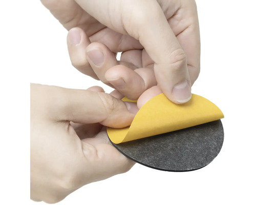 Osoba odstraňuje ochrannou fólii z kulatého nábytkového kluzáku