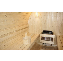 Vnitřní pohled na dřevěnou sudovou saunu s lavicemi, saunovými kamny a saunovým příslušenstvím