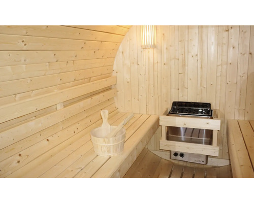 Vnitřní pohled na dřevěnou sudovou saunu s lavicemi, saunovými kamny a saunovým příslušenstvím