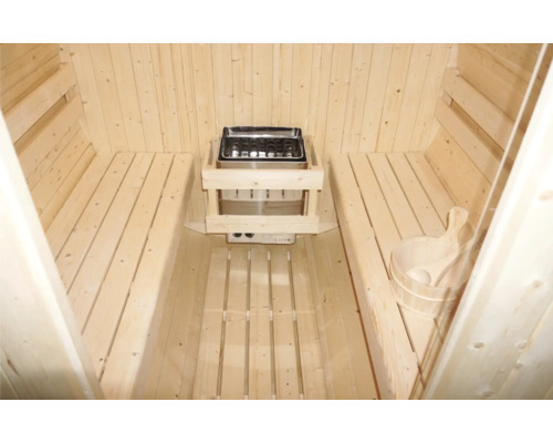 Vnitřní pohled na saunu s dřevěnými lavicemi, saunová kamna a saunový kbelík s naběračkou.