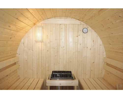 Vnitřní pohled na dřevěnou sudovou saunu s kamny, lavicemi, lampou a teploměrem