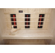 Interiér sauny s infračervenými zářiči, dřevěnými lavicemi a dřevěným vědrem s naběračkou.