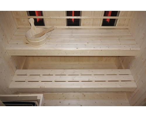 Interiér sauny s dřevěnými lavicemi, dřevěným vědrem a naběračkou