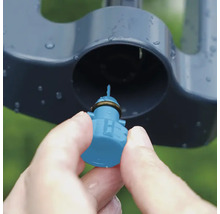 Detailní záběr ruky vkládající trysku do zavlažovače trávníku.