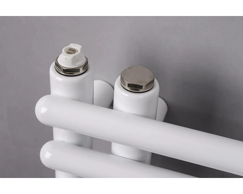 Detailní záběr na odvzdušňovací ventil a záslepku na bílém radiátoru.