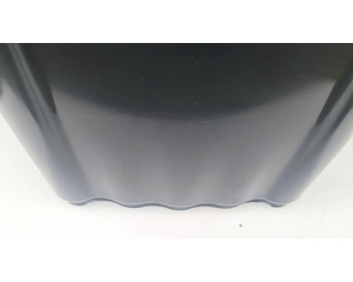 Detailní pohled na černý plastový květináč s vlnitým spodním okrajem.