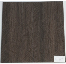 Čtvercová dlaždice v dekoru tmavého dřeva se strukturou chevron.